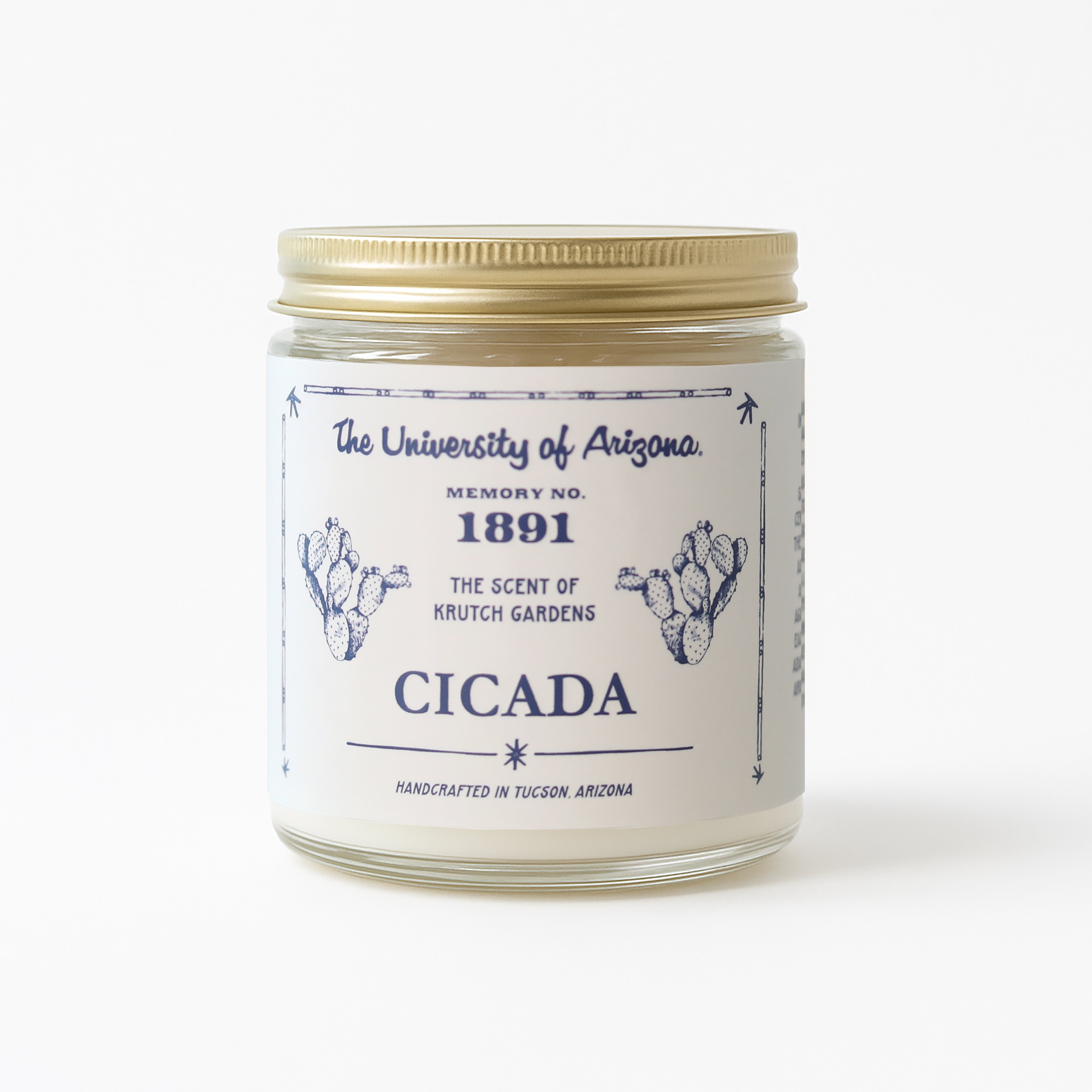 Glass candle jar with gold lid. Label is light cream color featuring 'The University of Arizona' and 'Cicada' logos on it. Candle label also shows the No. 1891 scent name on it. White background on image.