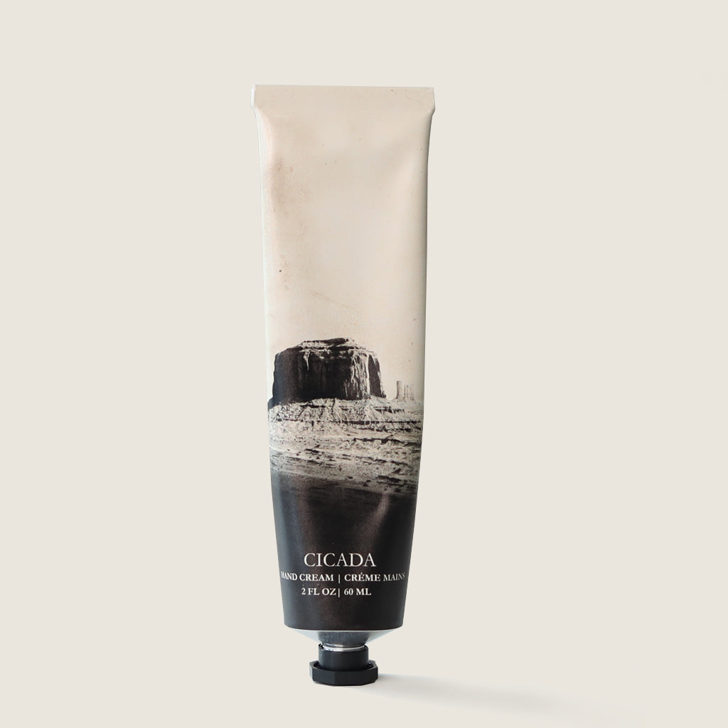 Product image showing an aluminum tube of hand cream with the No. 10 scent image on it which is a sepia-toned desert landscape illustration. The tube also is labeled 'CICADA' with the text 'hand cream and creme mains (French for hand cream)'. The package also shows the weight of the product, 2 oz or 60 ml. The product image has a cream colored background.
