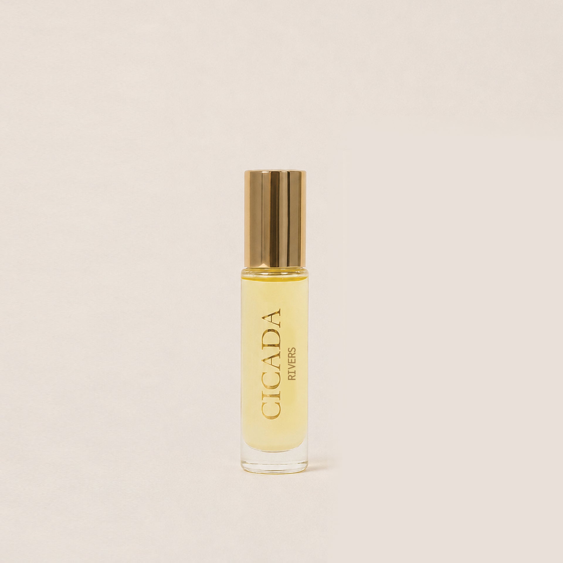 A small cylindrical glass bottle of Cicada Rivers fragrance oil with a metallic gold cap, set against a solid, warm off-white background.