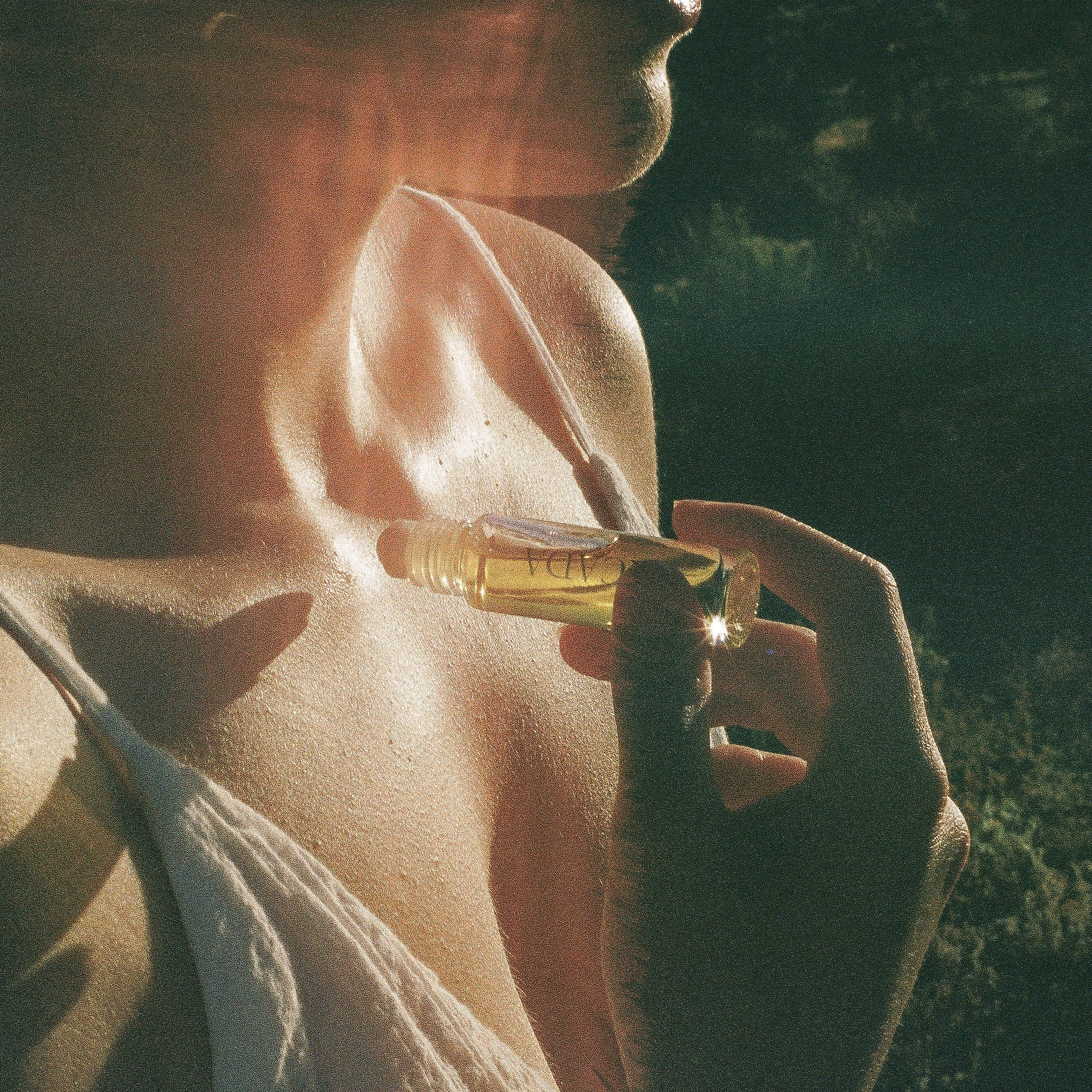 Lifestyle image of woman standing in desert applying CICADA perfume oil. 