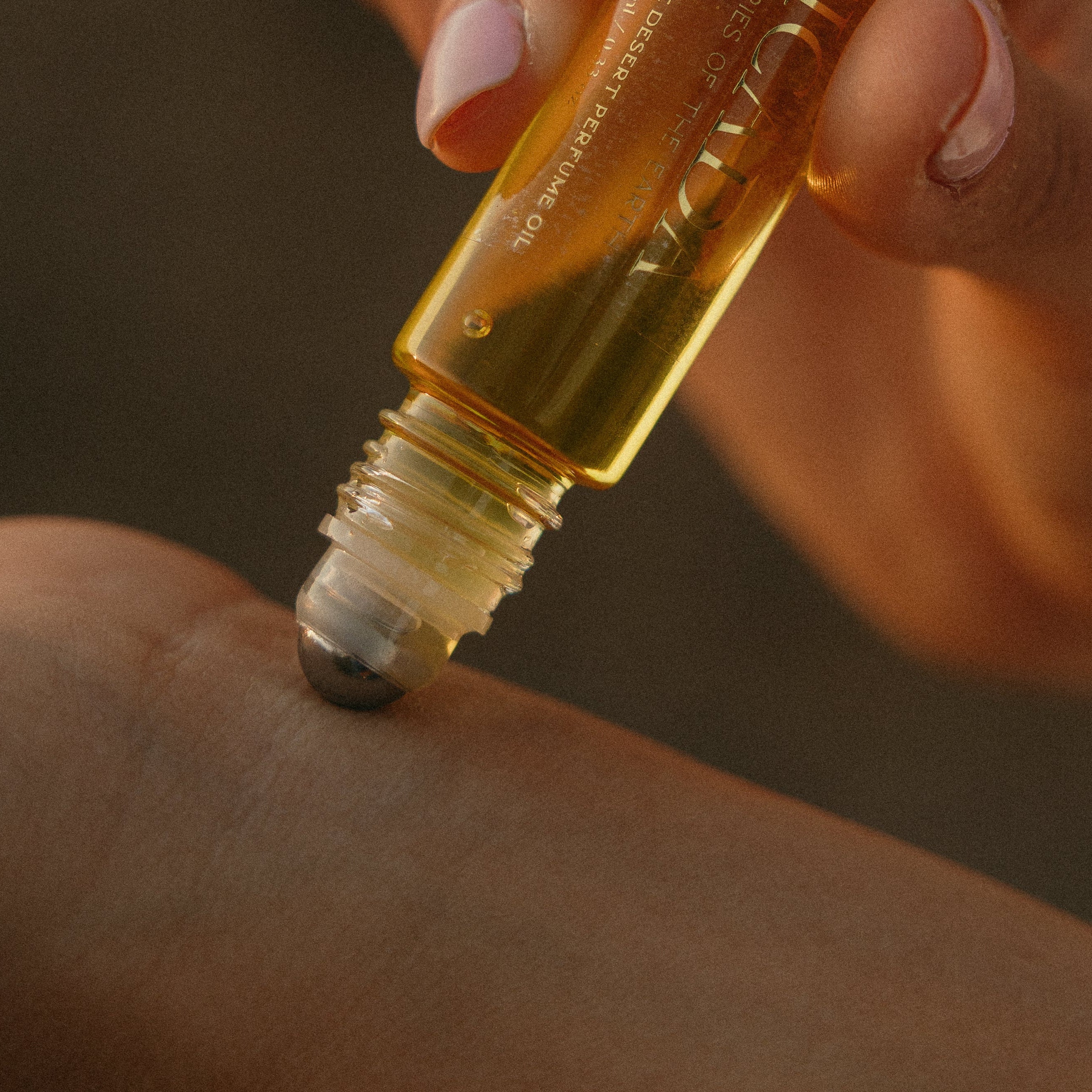 Lifestyle image of hand applying CICADA perfume oil to wrist. 