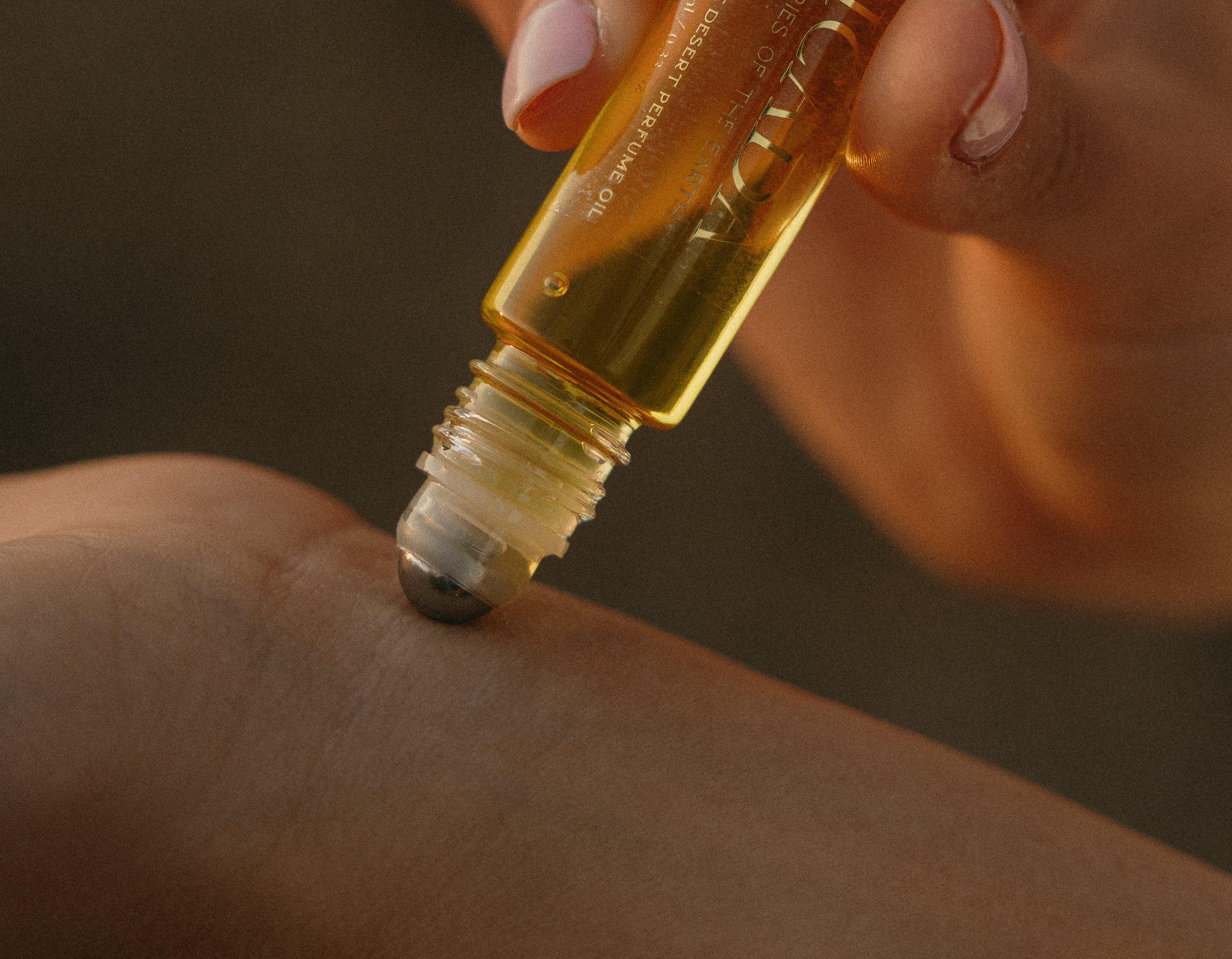 Lifestyle image of hand applying CICADA perfume oil to wrist. 