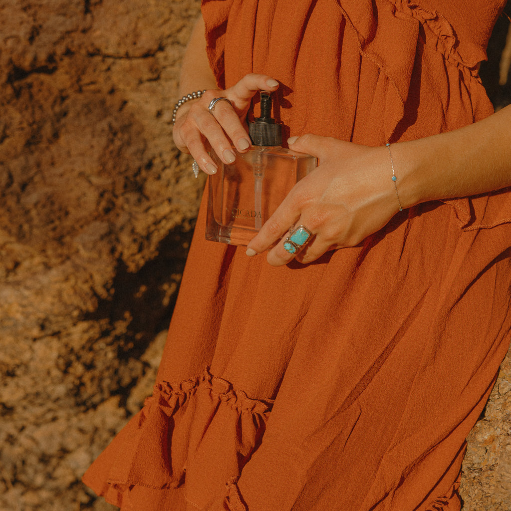 Person holding a CICADA hand soap bottle with a textured rock wall  background
