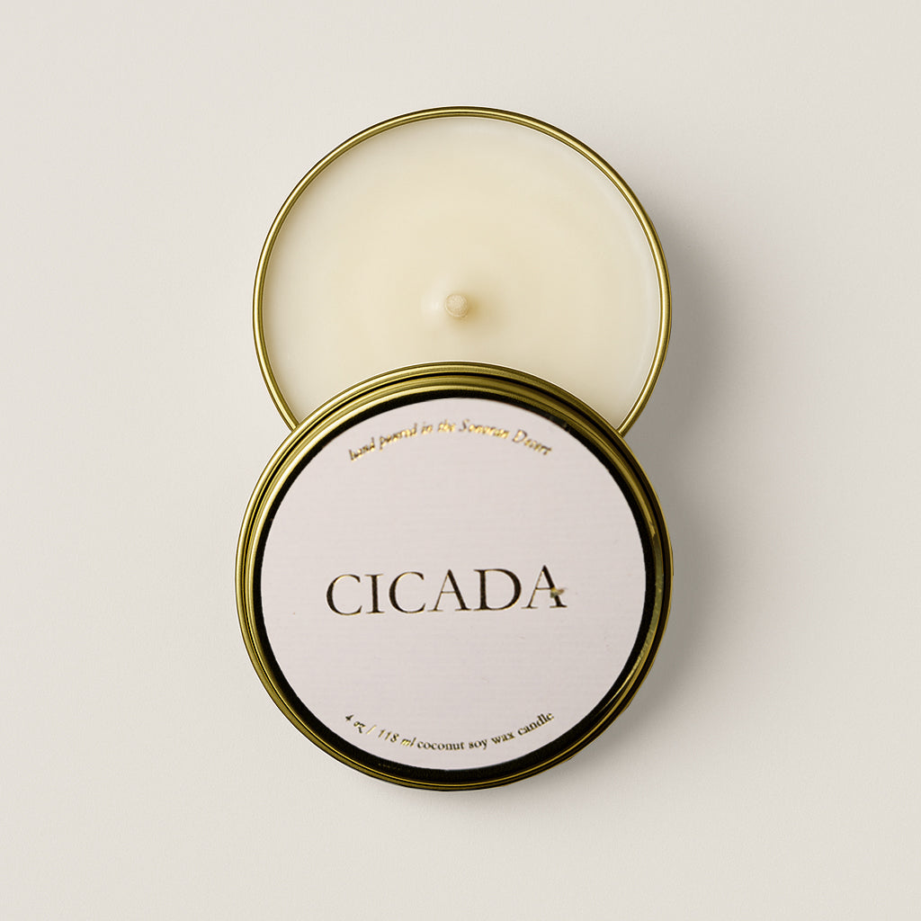 Image of candle in gold tin with 'CICADA' on candle lid